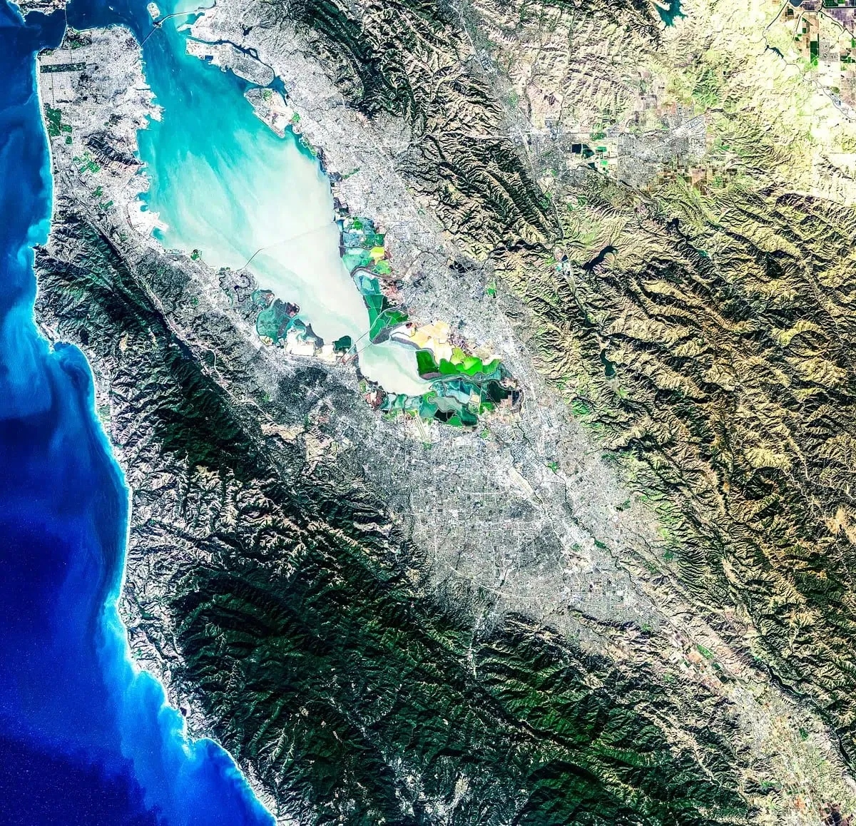 Satellite image of a coastal city, bay, and surrounding terrain